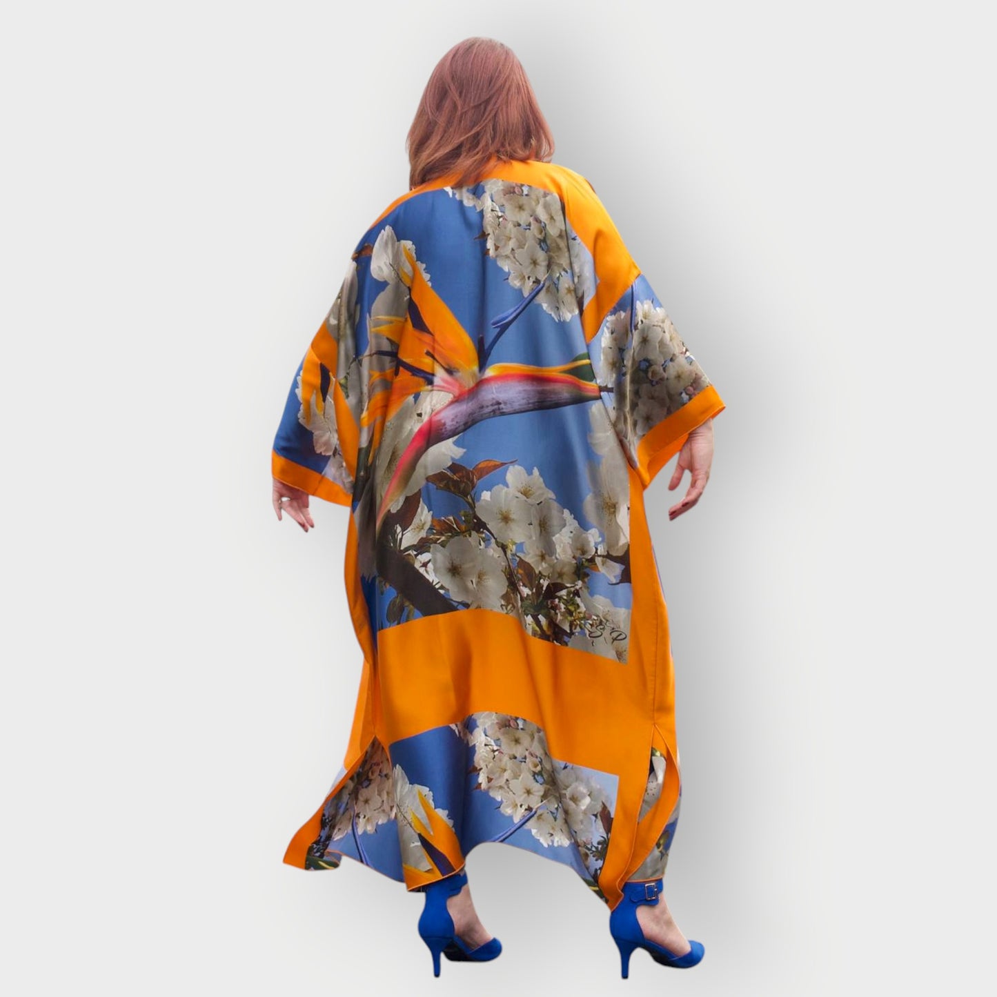 Model showcases the Bird of Paradise Cherry Blossom Silk Kimono from the back while wearing blue shoes, emphasizing the vibrant colors and elegant design.