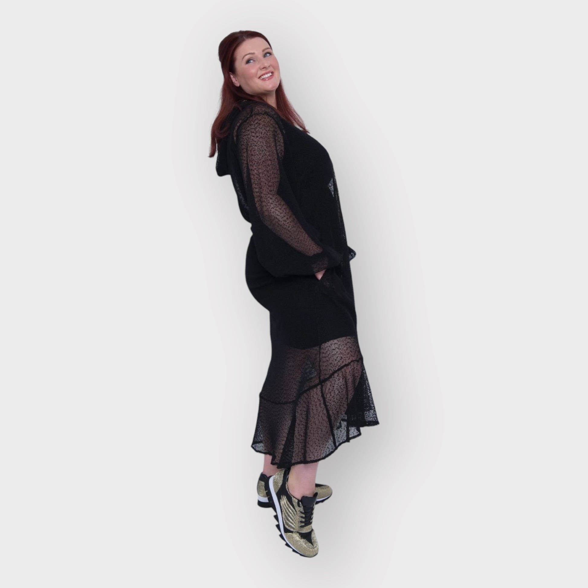 Plus Size Aphrodite Black Holiday Resort Dress with hoodie and black undergarment shown from the side, paired with gold and black sneakers.