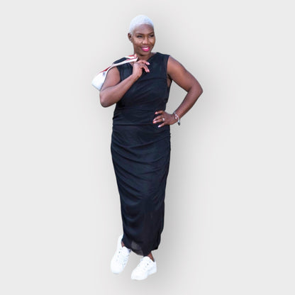 Women's Boudicca Summer Black Ruched Bodycon dress styled with a white handbag and white sneakers for a chic, modern ensemble.