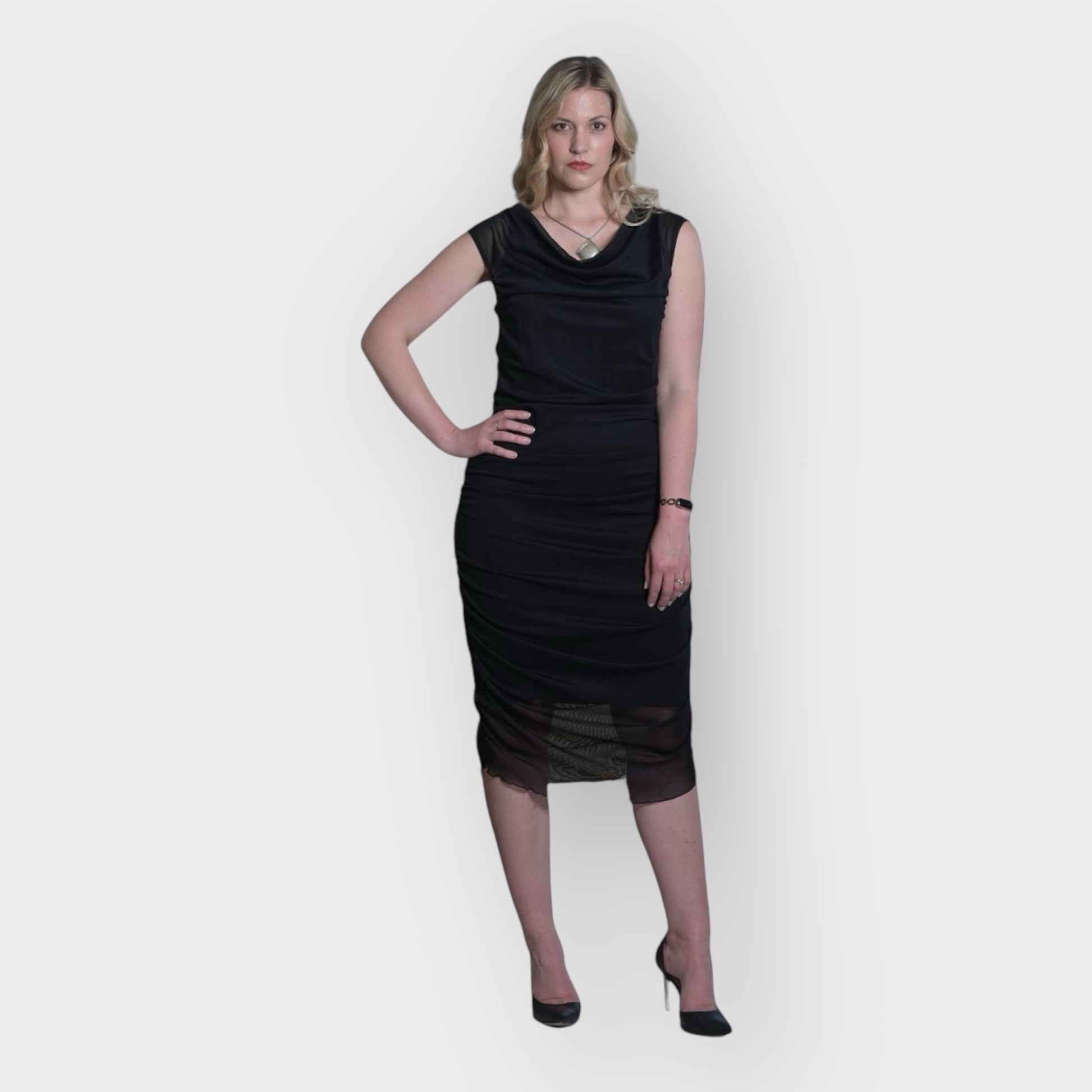 Women's Boudicca Summer Black Ruched Bodycon dress styled with a silver necklace and black heels for an elegant, sophisticated look.
