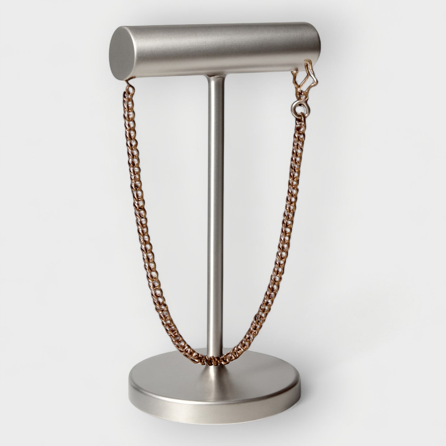 Metal Necklace on a metal stand against a white background
