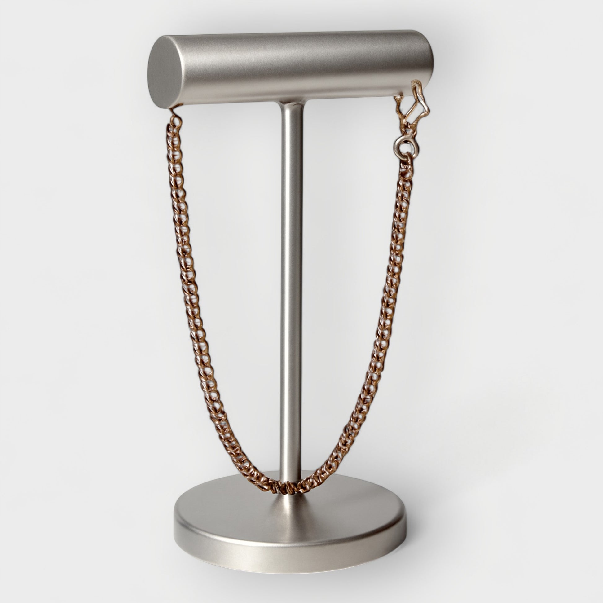Metal Necklace on a metal stand against a white background
