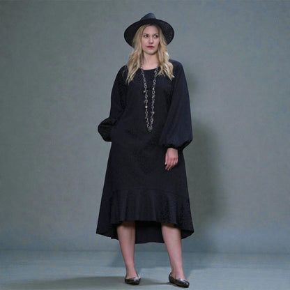 Women's Aphrodite Black Leopard Jacquard Dress styled with a silver chain necklace, black hat, and silver flats for a chic, coordinated look. Gray background.