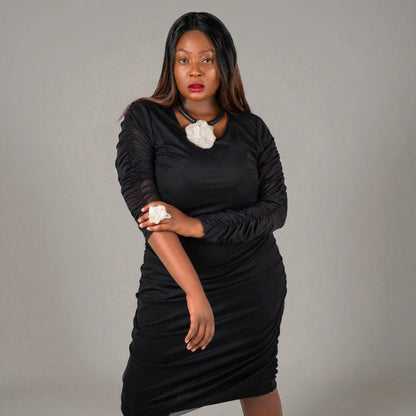 Plus Size Woman wearing a black ruched midi dress with quartz jewellery by Veronique Designs on a gray background