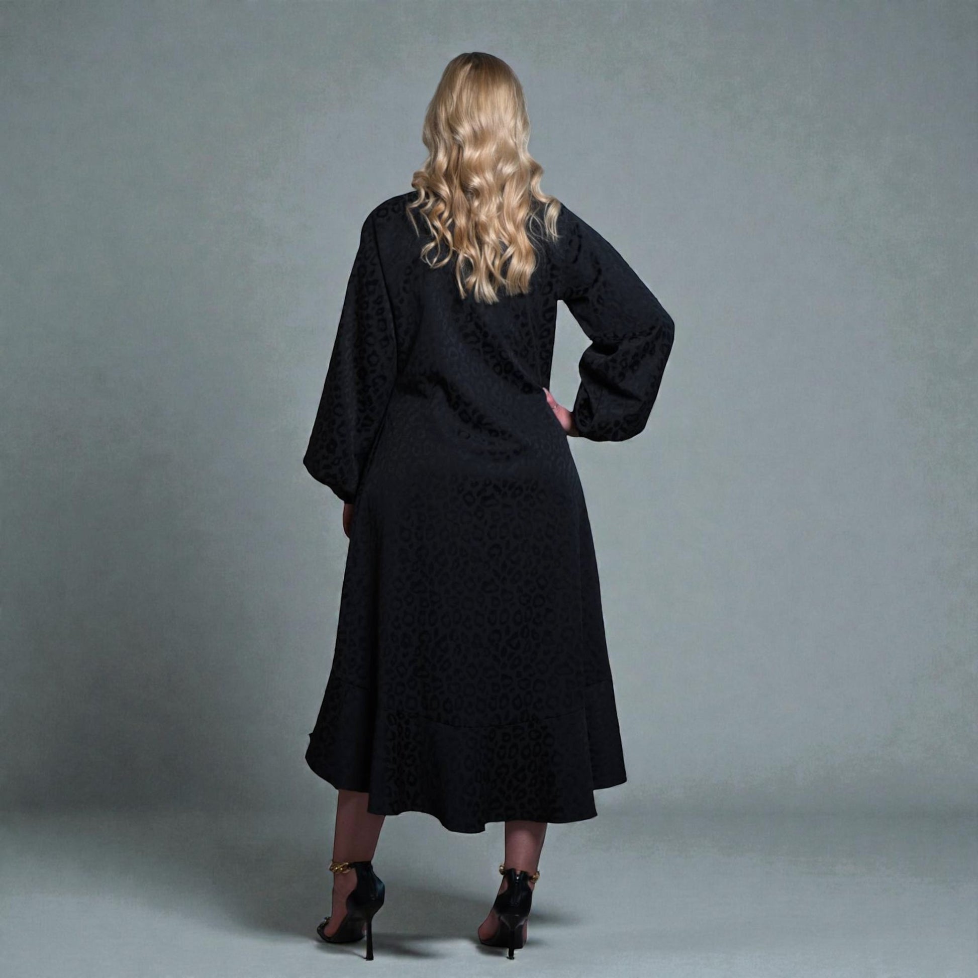 Women's Aphrodite Black Leopard Jacquard Dress styled with gold chain heels for a chic, coordinated look. Gray background.