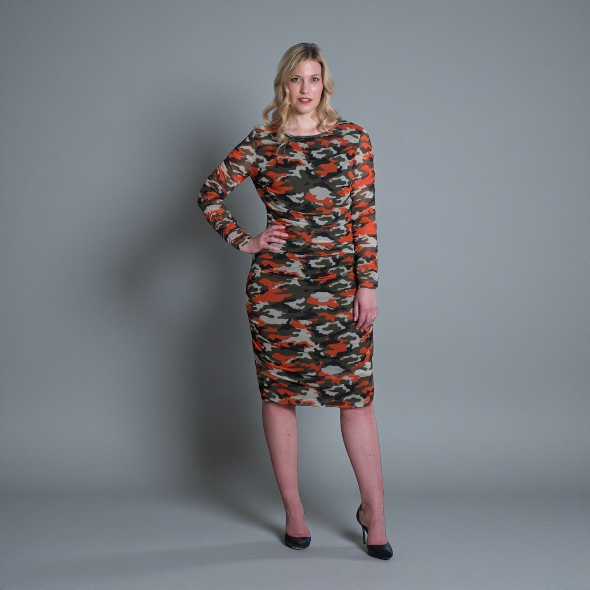 Women's Mid Size Orange Green Grey Camouflage Bodycon Midi Dress styled with black heels for a modern, stylish look.Plain background.