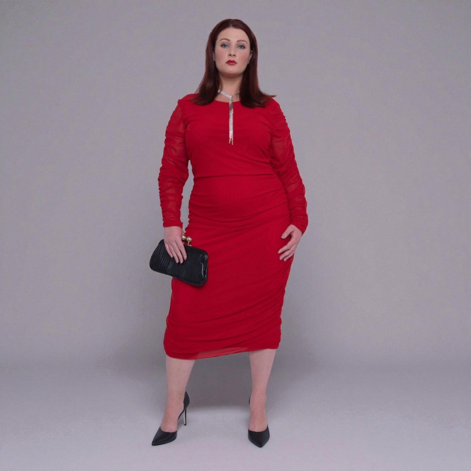 Plus Size Woman wearing a red dress with sheer sleeves against a gray background