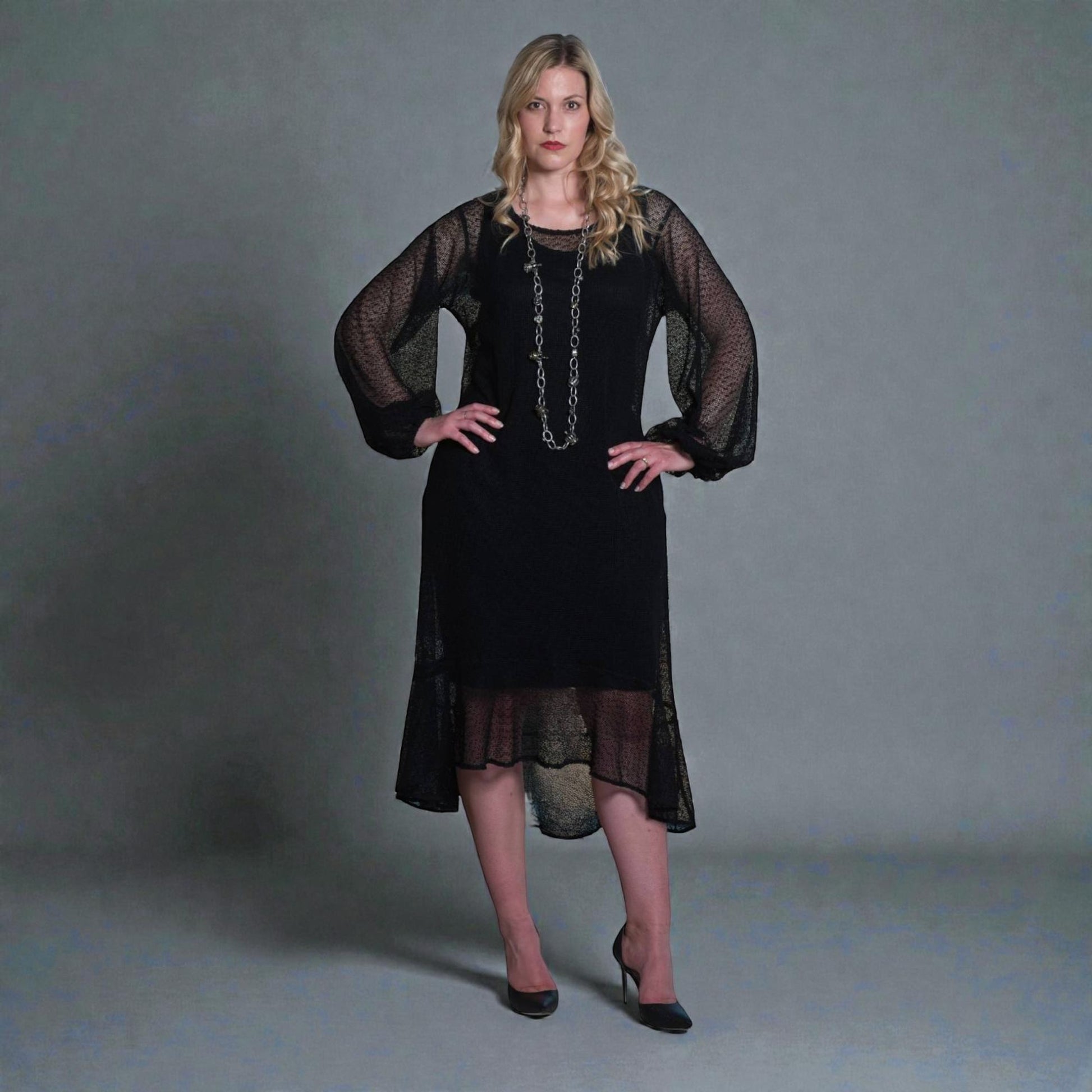 Women's Aphrodite Black Holiday Resort Dress with black undergarment, accessorized with a silver chain necklace and styled with black heels.