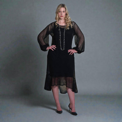 Women's Aphrodite Black Holiday Resort Dress with black undergarment, accessorized with a silver chain necklace and styled with black heels.