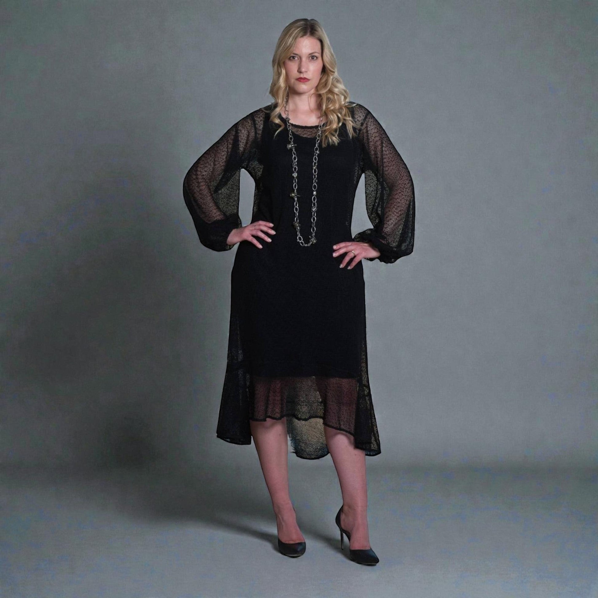 Women's Aphrodite Black Holiday Resort Dress with black undergarment, accessorized with a silver chain necklace and styled with black heels.