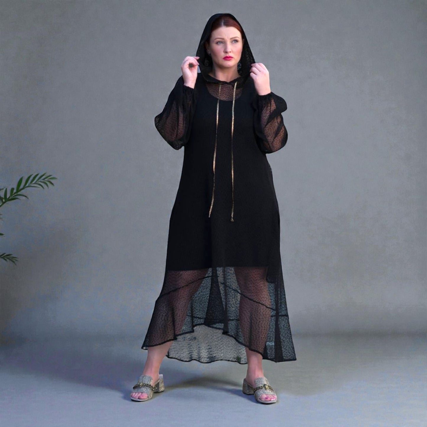Plus Size Woman wearing a black dress with sheer overlay against a gray background.