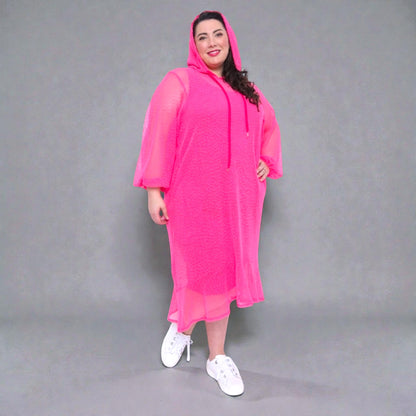 Women's Plus Size Aphrodite Hot Pink Holiday Resort Midi Dress with hoodie and hot pink undergarment, paired with white sneakers for a casual look.Grey Background.