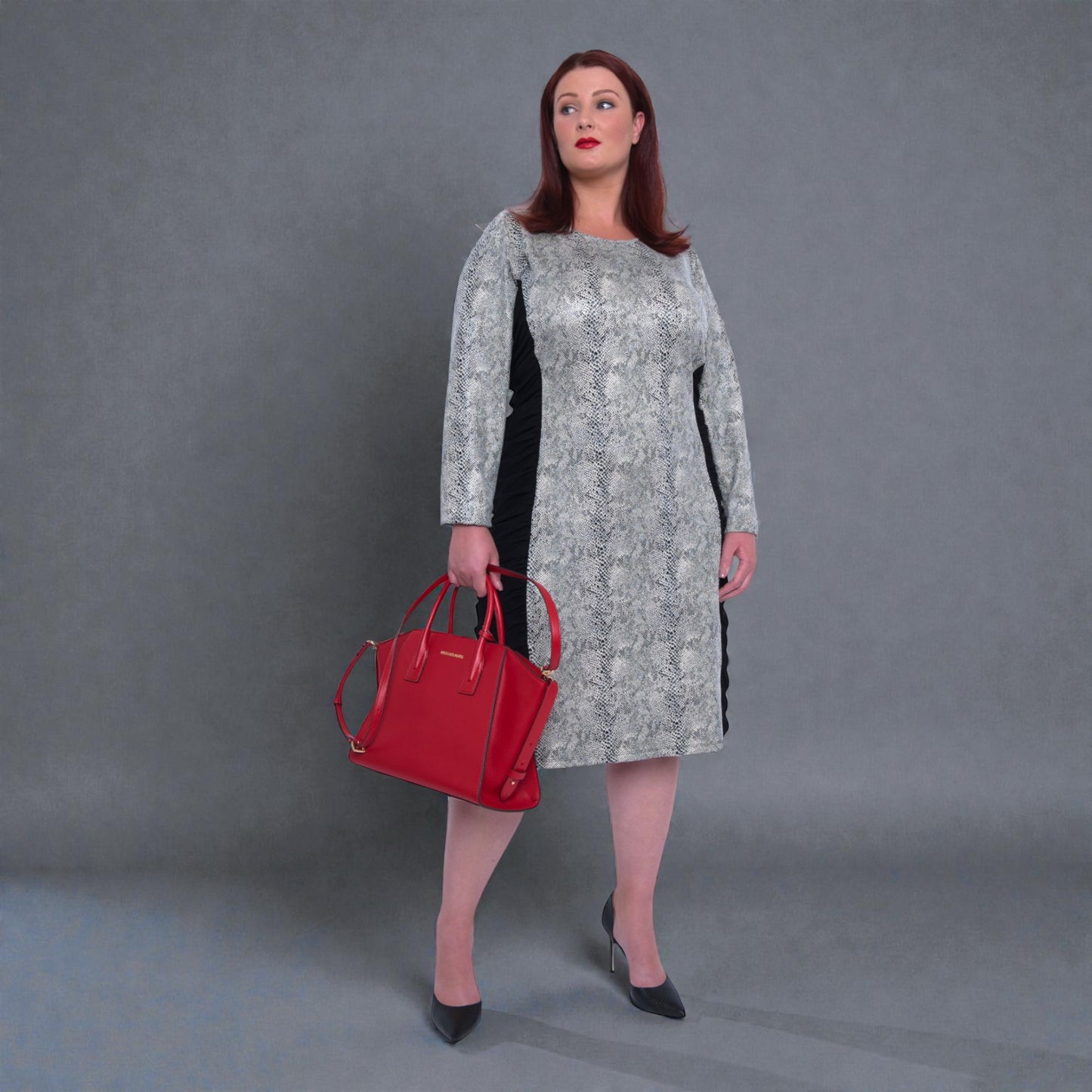 Women's Plus Size Black White Animal Print Bodycon Midi Vegan Leather Dress styled with a red Michael Kors handbag and black heels for an elegant look.