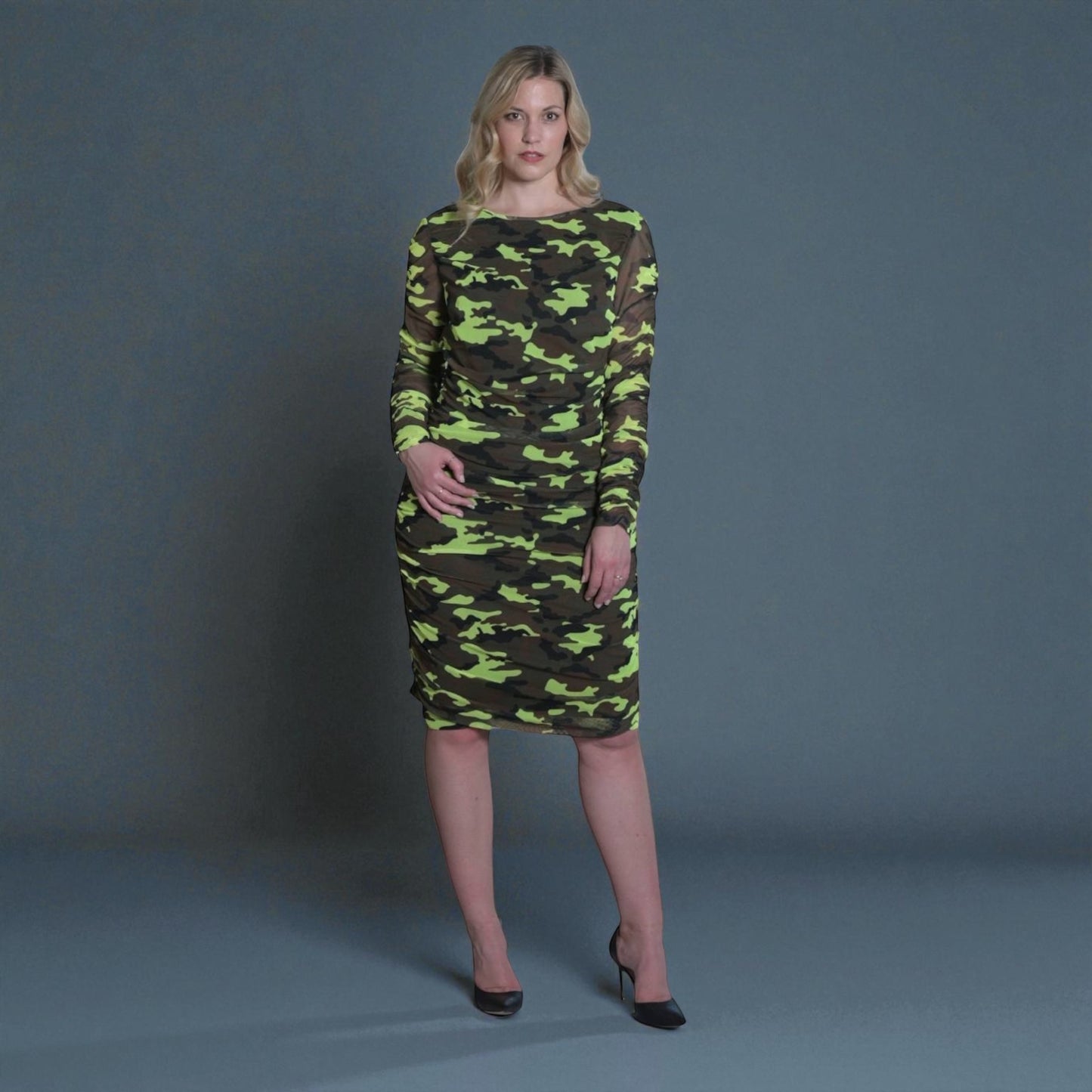 Women's Mid Size Neon Lime Brown Black Camouflage Bodycon Midi Dress styled with black heels for a bold and chic look.Grey Background.