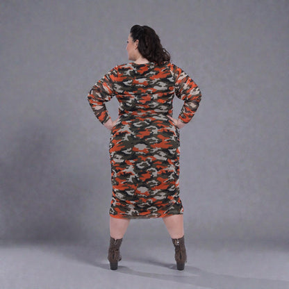Plus Size Woman in an Orange Green Grey Camouflage Bodycon Midi Dress styled with green boots for a modern, stylish look.Plain background.