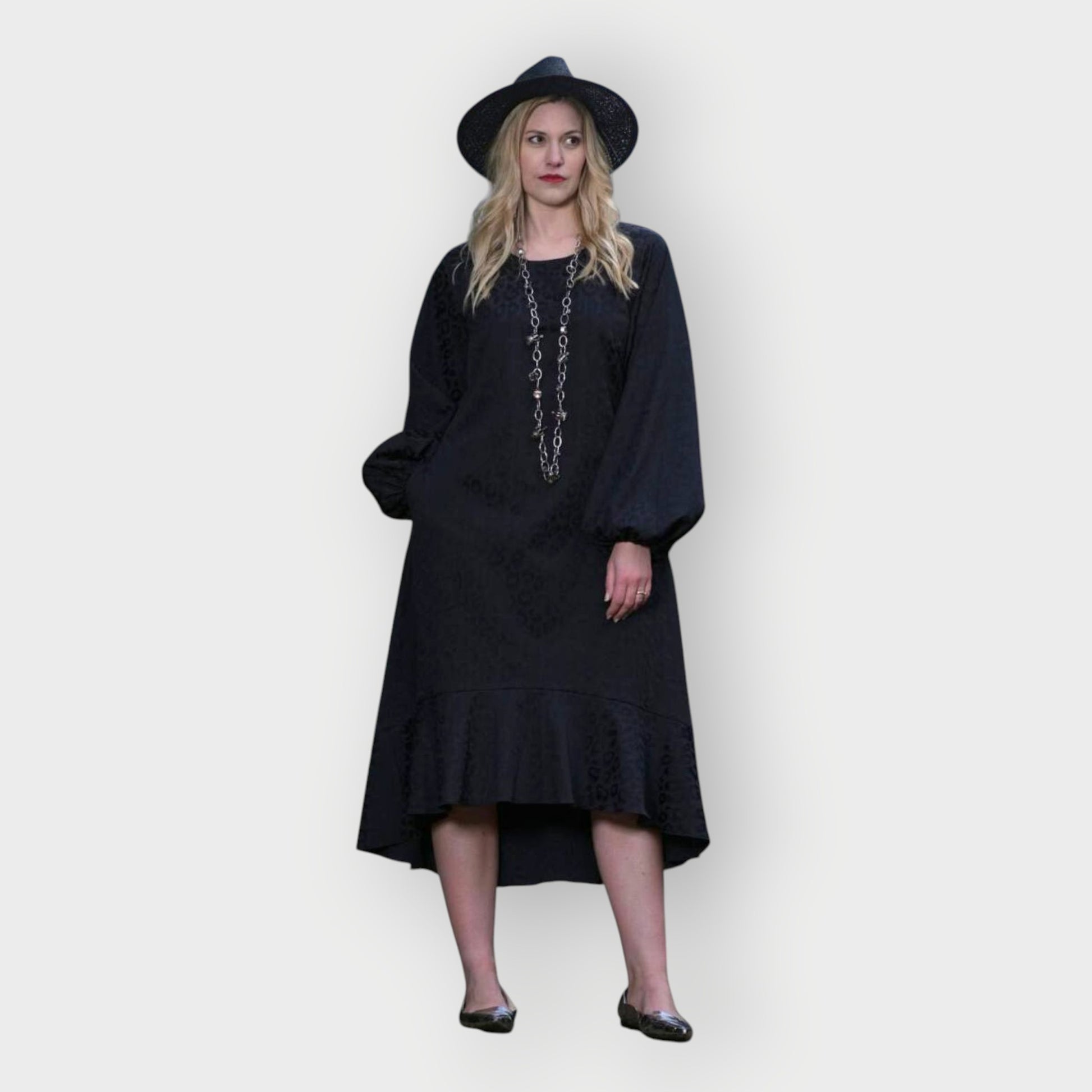 Women's Aphrodite Black Leopard Jacquard Dress styled with a silver chain necklace, black hat, and silver flats for a chic, coordinated look.