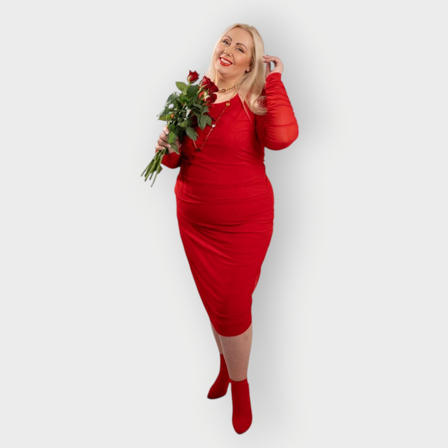 Women's Red Plus Size Boudicca Ruched Bodycon Midi Dress styled with gold jewelry and red heels, holding red roses for a romantic touch.