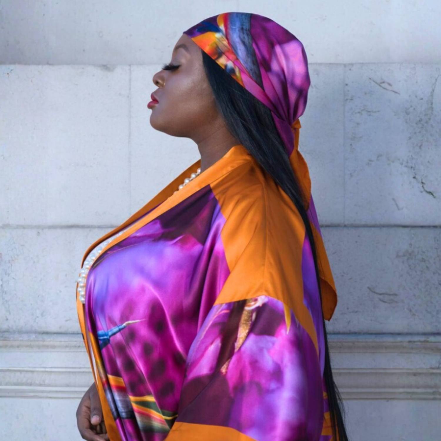 Woman wearing a colorful Bird of Paradise Pink Purple Silk Scarf  and Kimono against a light-colored wall.