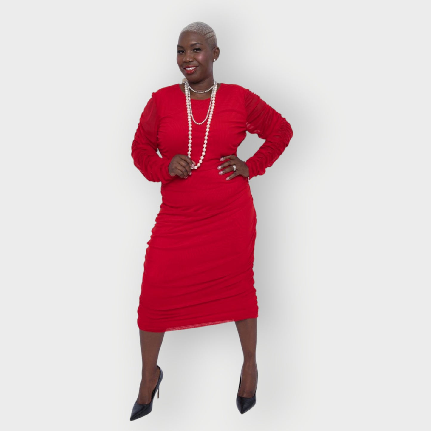 Women's Red Plus Size Boudicca Ruched Bodycon Midi Dress styled with pearl  jewelry and black heels. White Background