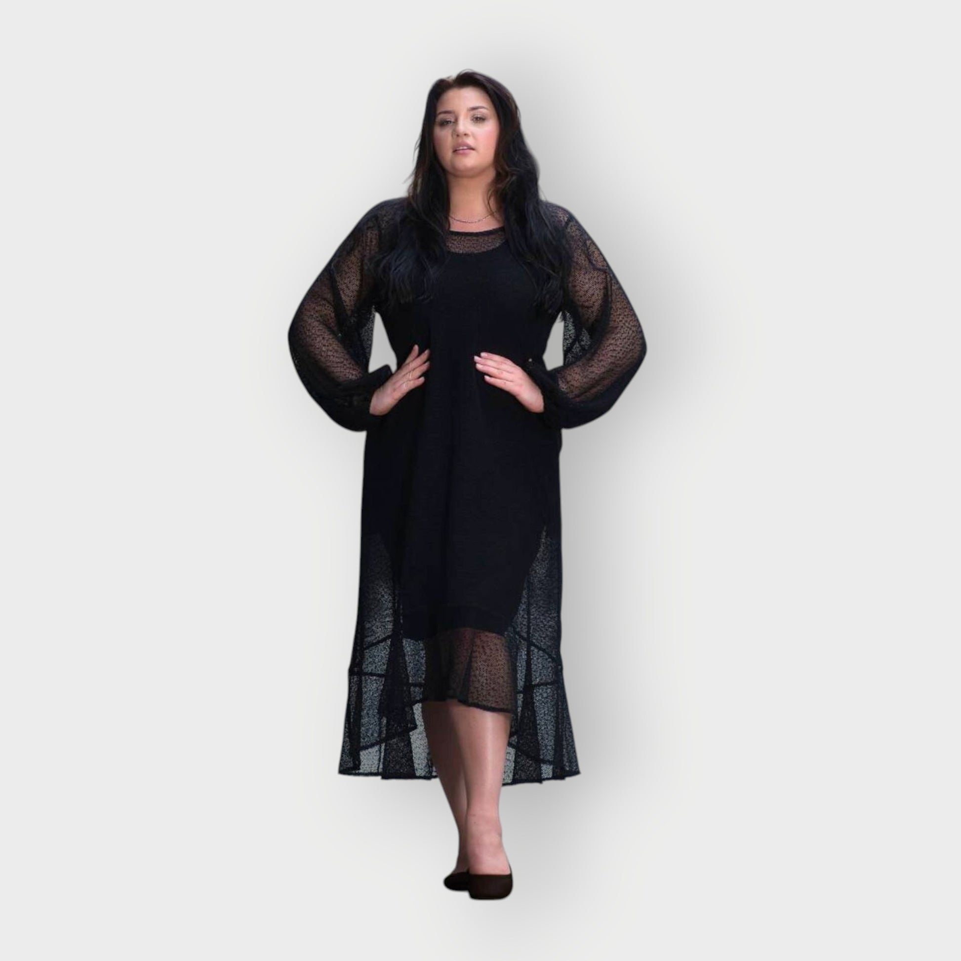 Woman wearing a black dress with sheer sleeves and hem on a white background