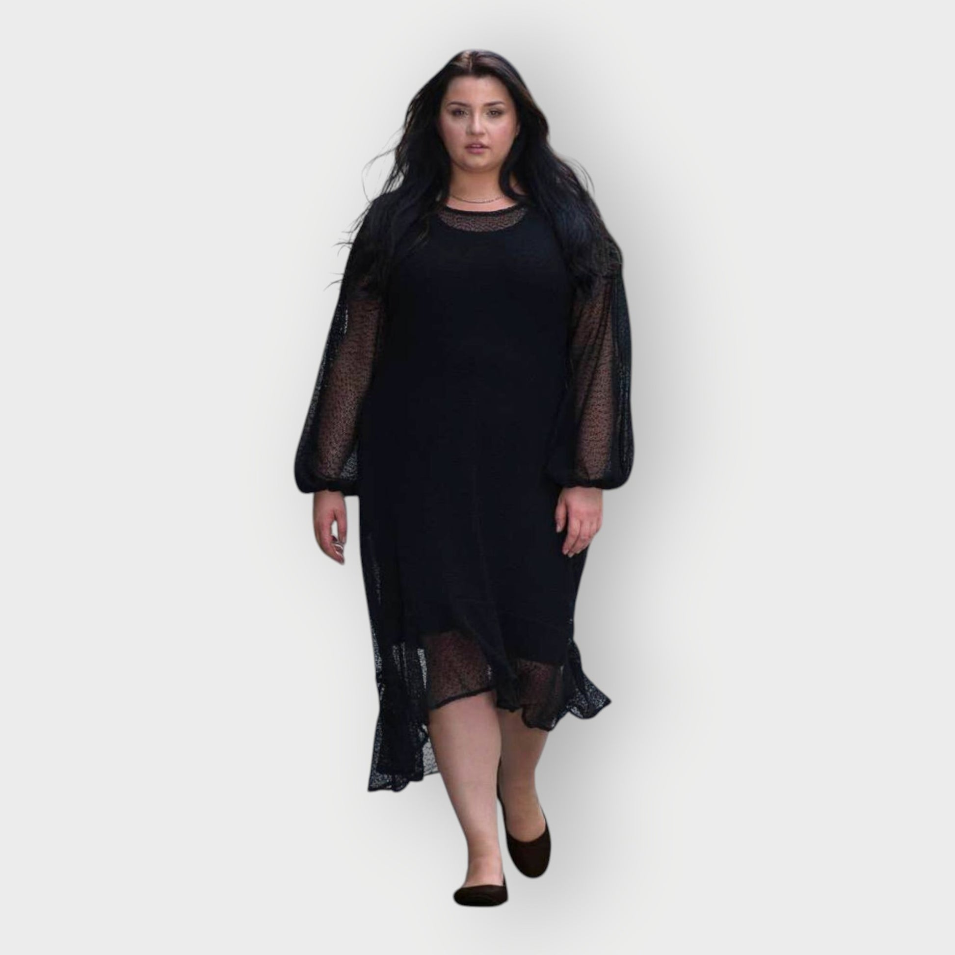 Woman wearing a black dress with sheer sleeves on a white background