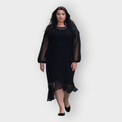 Woman wearing a black dress with sheer sleeves on a white background