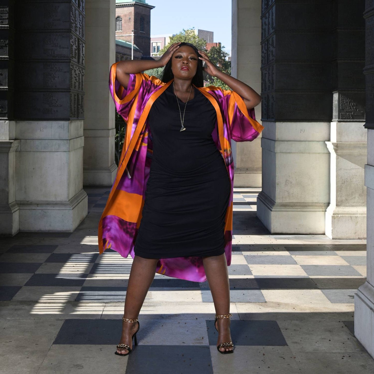 Women's Black Plus Size Ruched Bodycon Midi Dress styled with a pink purple silk Kimono for a pop of color and gold chain heels for an elegant touch.