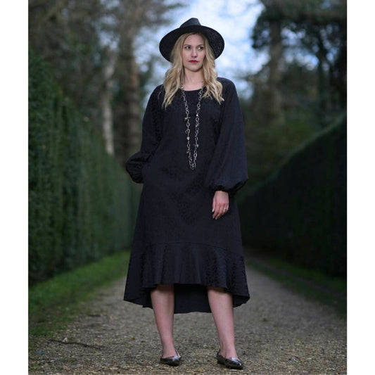 Women's Aphrodite Black Leopard Jacquard Dress styled with a silver chain necklace, black hat, and silver flats for a chic, coordinated look.