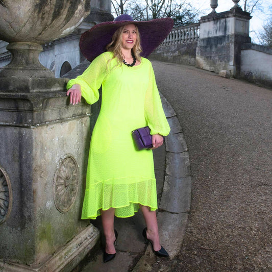 Women's Aphrodite Neon Lime Holiday Resort Dress with matching neon lime undergarment, styled with a purple sunhat, handbag, and black heels.