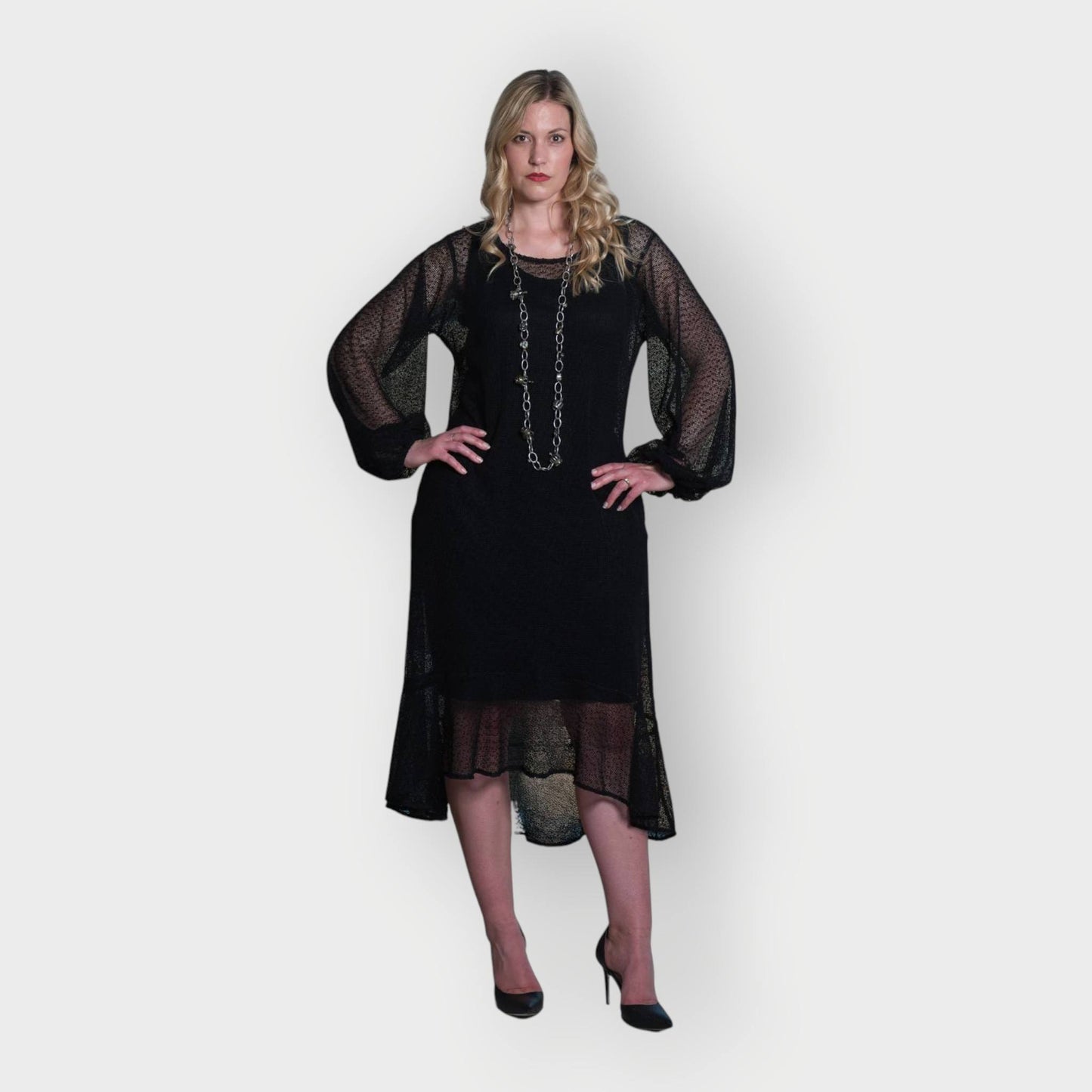 Women's Aphrodite Black Holiday Resort Dress with black undergarment, accessorized with a silver chain necklace and styled with black heels.