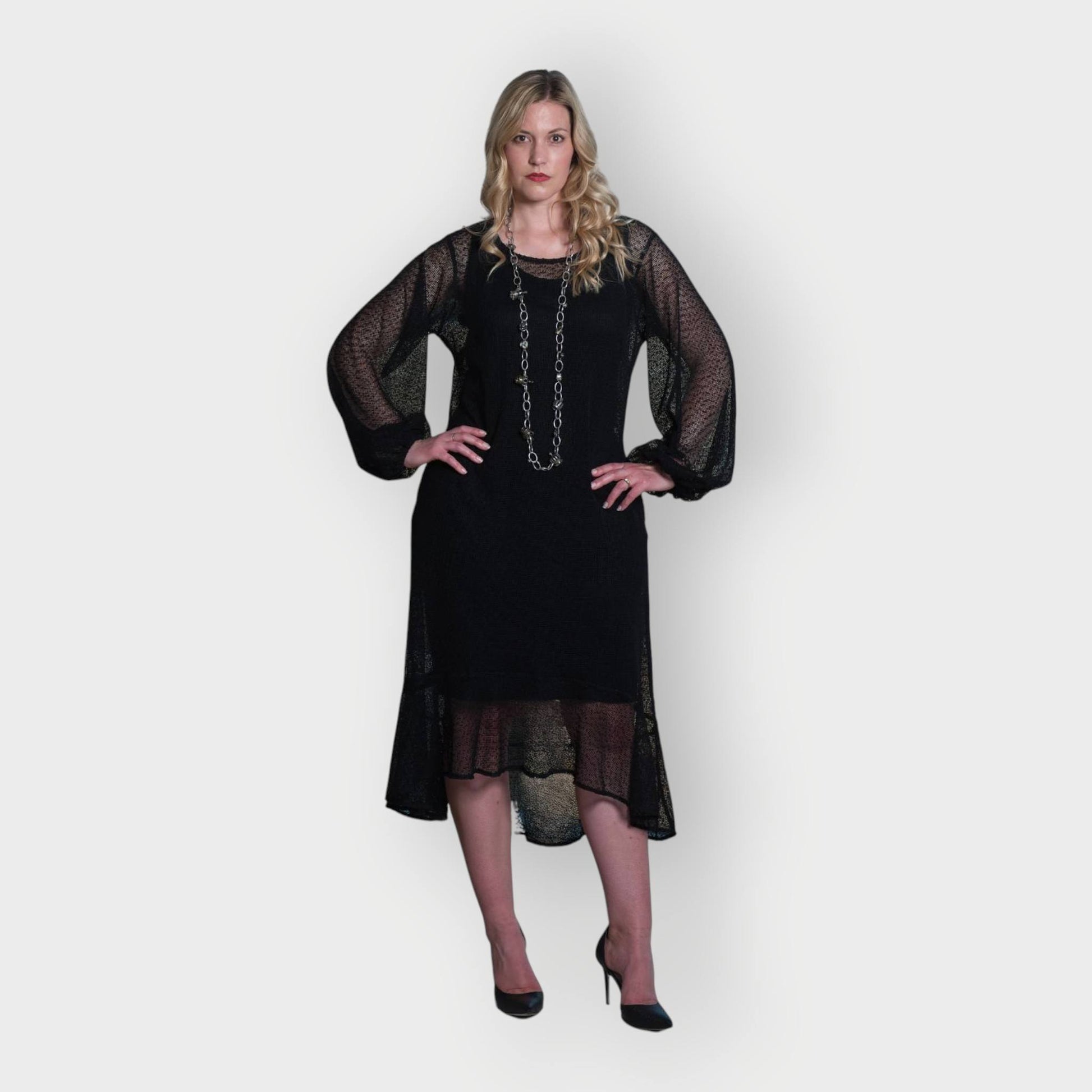 Women's Aphrodite Black Holiday Resort Dress with black undergarment, accessorized with a silver chain necklace and styled with black heels.