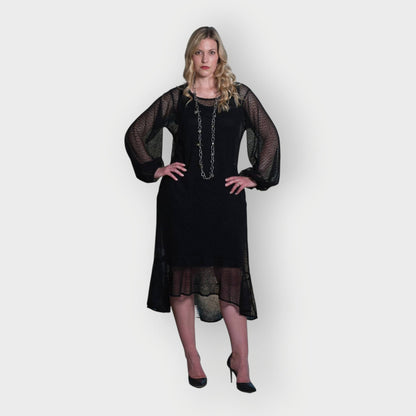 Women's Aphrodite Black Holiday Resort Dress with black undergarment, accessorized with a silver chain necklace and styled with black heels.