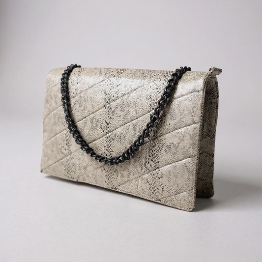 Quilted clutch bag with snake print and black chain strap on a light gray background