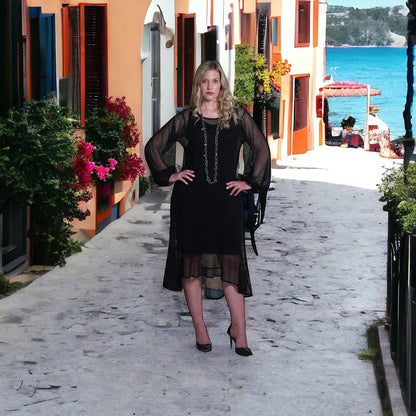 Sylvia Piechulla black mesh midi dress with bishop sleeves and flounce hem worn by a blonde model on a sunny street.