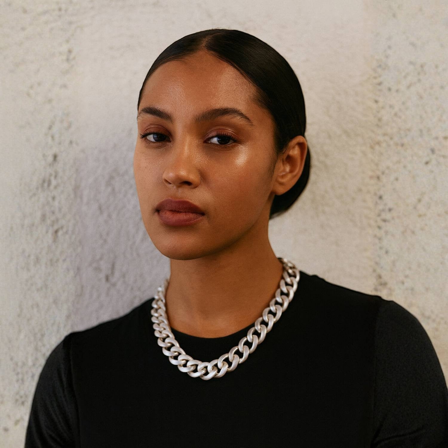 Model wearing a Sylvia Piechulla chunky silver aluminium chain necklace with oversized links against a textured wall.