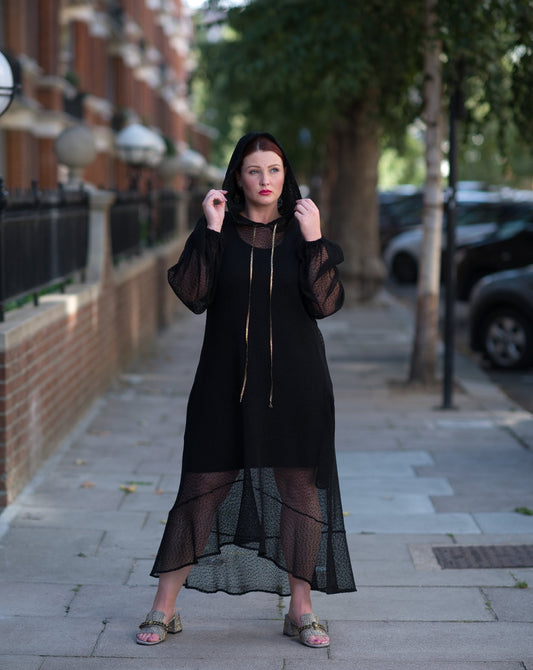 Plus Size Aphrodite Black Holiday Resort Dress with hoodie and black undergarment, styled with golden sandals for a chic and comfortable look.