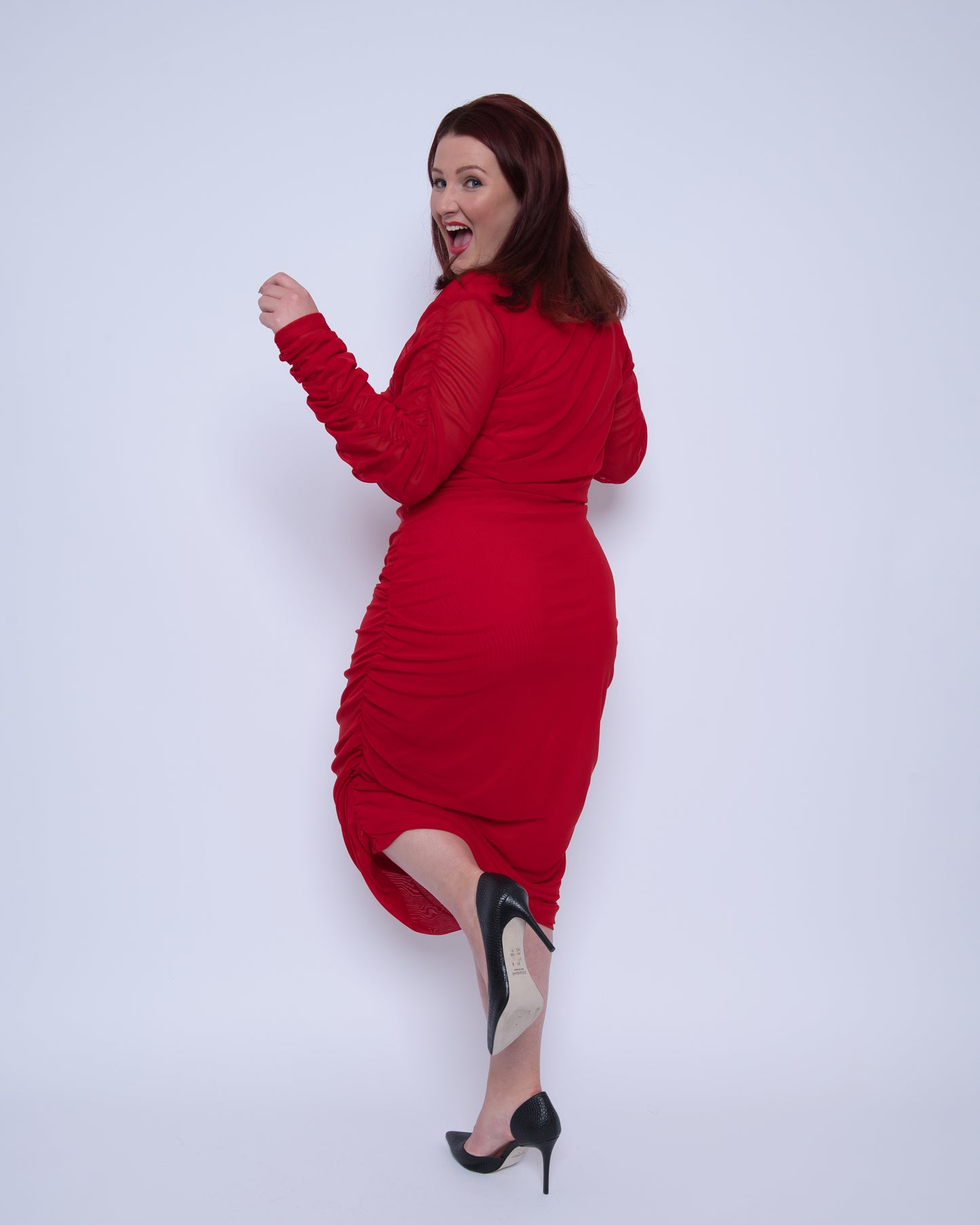 Women's Red Plus Size Boudicca Ruched Bodycon Midi Dress shown from the back, styled with black heels for a sophisticated, elegant look.