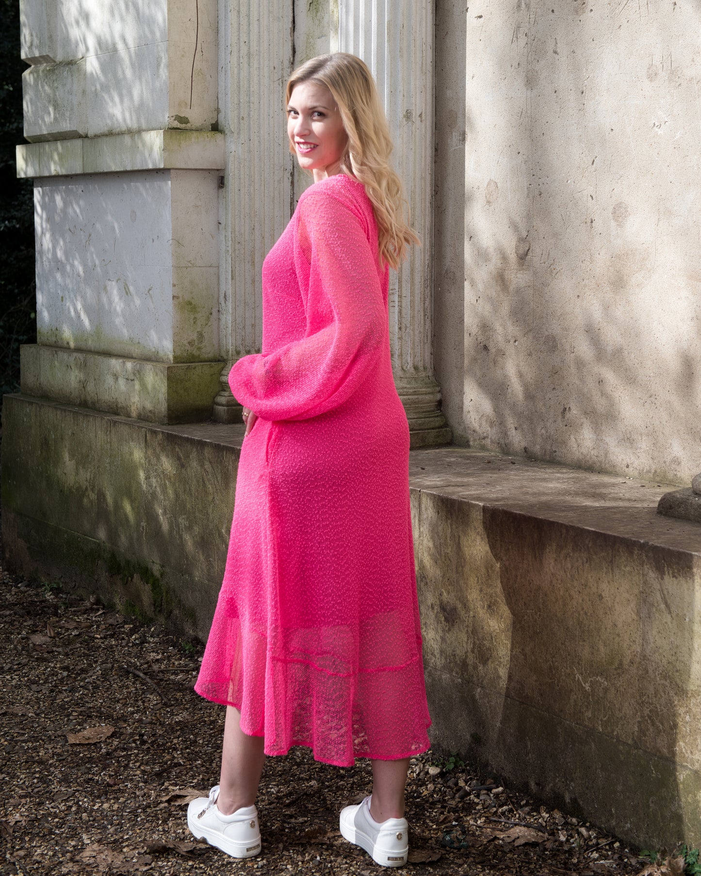Women's Aphrodite Hot Pink Holiday Resort Dress with a hot pink undergarment shown from the side, paired with white sneakers